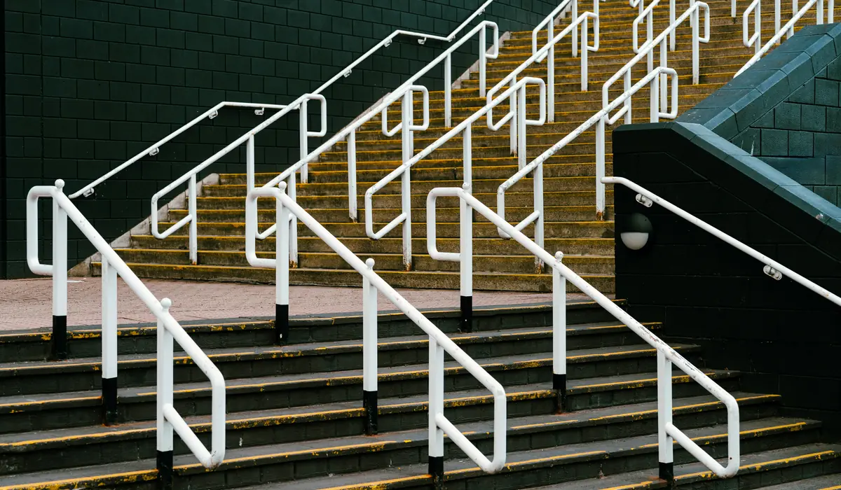 Escaliers extérieurs équipés de mains courantes blanches, aux nez de marche soulignés de jaune